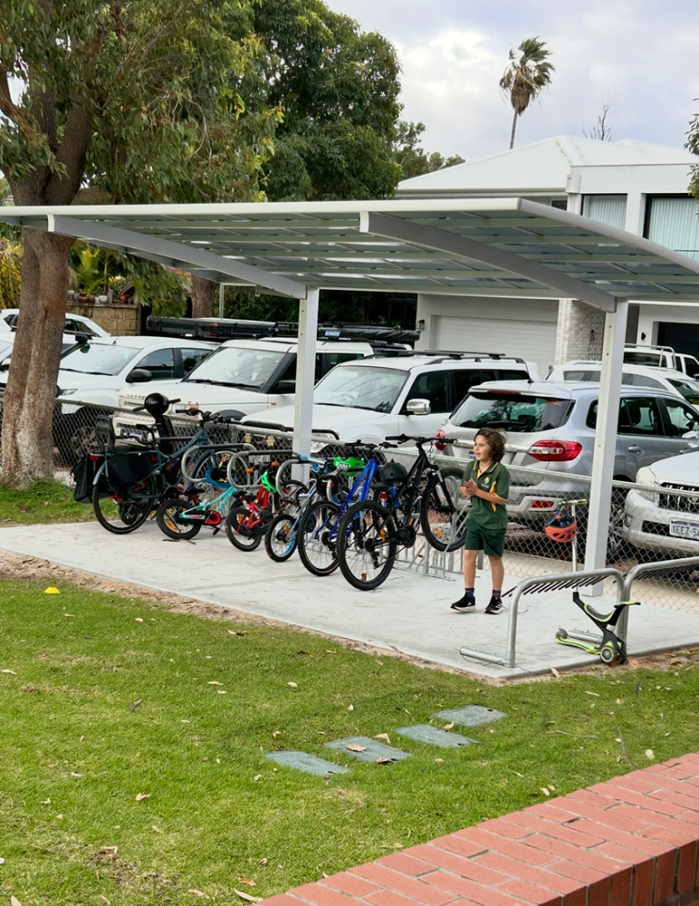 A student standing next to bicycles parked under a bike shelter